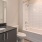 Large well lit bathroom with large mirror and brown cabinets 