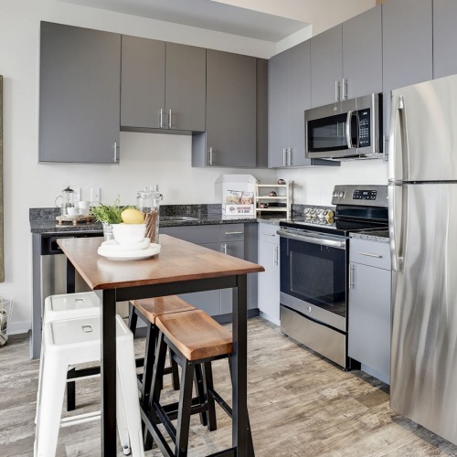 Spacious and well lit kitchen with wood floors and stainless steel appliances. 