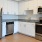 Spacious and well lit kitchen with wood floors and stainless steel appliances. 